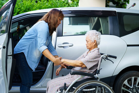 Caregiver help Asian elderly woman disability patient use wheelchair to get in car.