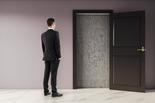 Businessman standing in modern interior looking at open door revealing blocked concrete exit symbolizing deadlock and challenge scenario.