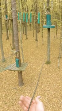 Pulling rope on adventure park course between high in trees POV