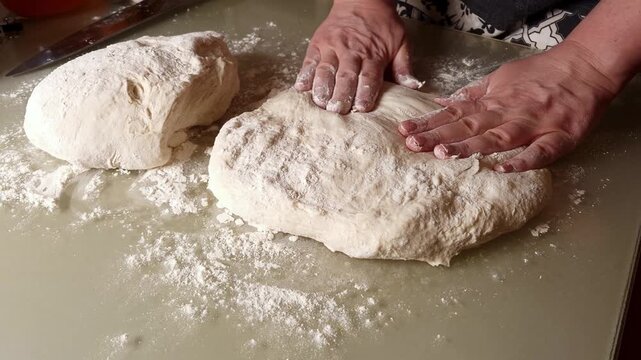 Hands skillfully work a ball of dough on a floured surface, demonstrating the process of kneading for baking bread or pastries