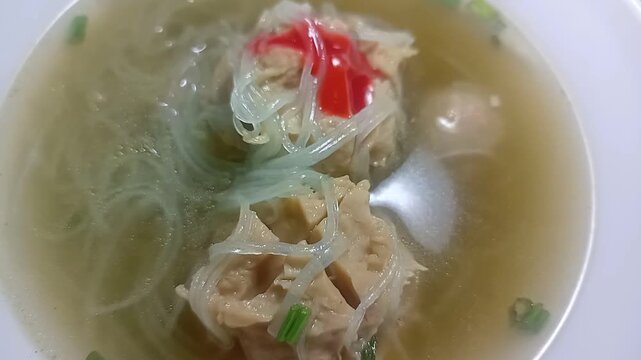Freshly served bowl of Indonesian Bakso meatball soup with noodles and celery