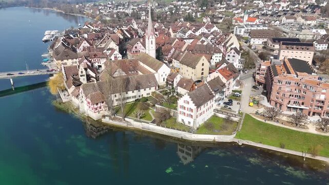 Aerial view of Stein am Rhein old town, church steeple, bridge, riverfront buildings, and surrounding hills.