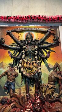 Idol of hindu goddess maa kali made with black granite marble decorated with colours and light at temple.