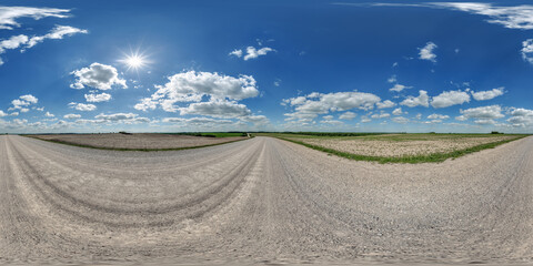 Fototapeta premium hdri 360 panorama view on gravel country roads among fields with beautiful clouds in sky in equirectangular full seamless spherical projection, ready for VR AR or skydome replacement