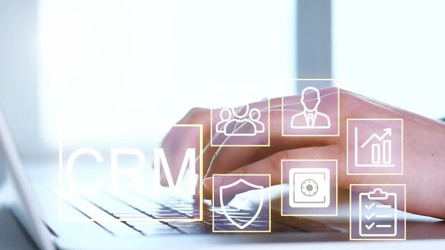 Hands type on a laptop while icons for CRM, charts, and documents appear on the screen, showing a focus on business tasks and digital tools.