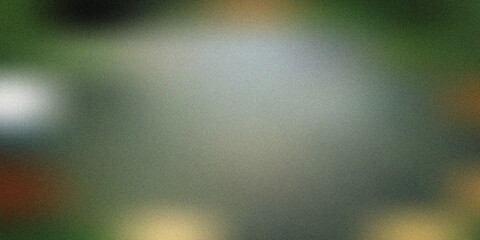 Abstract blurred background featuring a soft gradient of dark green and grey tones with a subtle grainy texture and glowing light spots, artistic backdrop. © Uilex 