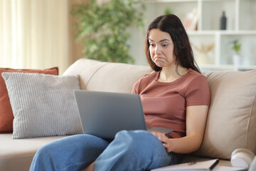 Fototapeta premium Perplexed young student checking laptop content