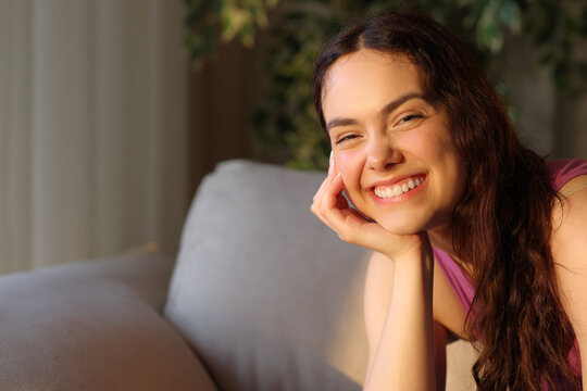 Happy young woman with perfect smile looks at you at sunset