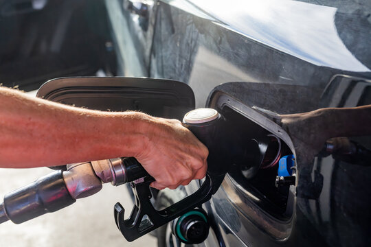 Hand of a woman at a fuel bowser filling a car with diesel