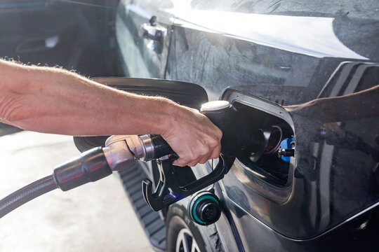 Hand of a woman at a fuel bowser filling a car with diesel