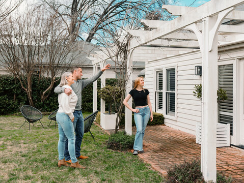 Happy family gathered in the patio of their new home with adult man pointing towards patio rafter