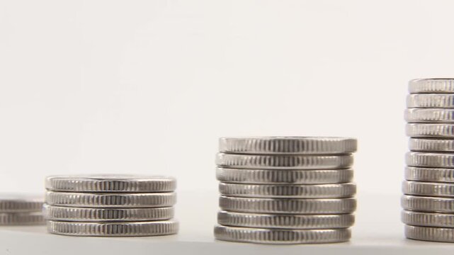 Stacks of silver coins stand at different heights as the camera focus moves between the stacks in the foreground and background, savings and investment concepts. looped video