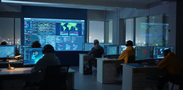 Network operations center with team monitoring global data on large screens
