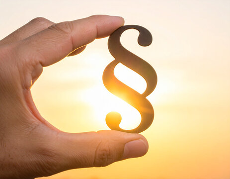 Hand hält Paragraphenzeichen in die Sonne