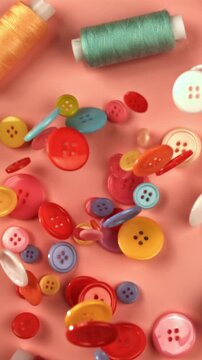 Multi-colored sewing buttons fall on a red table. Filmed on a high-speed camera at 1000 fps. High quality FullHD footage