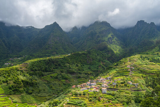 Mountain landscape with a small village on a slope with lush vegetation and terraces, isle of Madeira Portugal