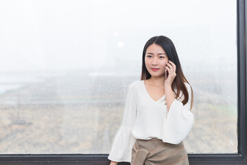 Fototapeta premium Businesswoman talking on phone by rainy office window