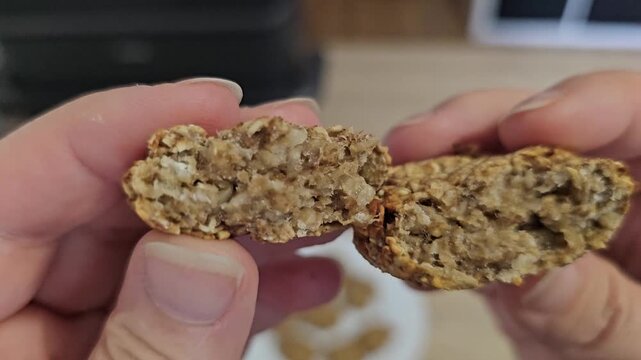 Person breaking a homemade oatmeal cookie in half