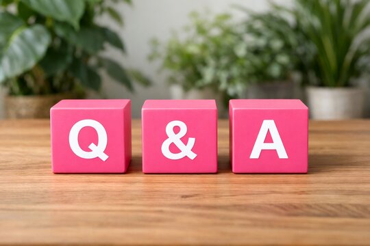 観葉植物を背景にした木のテーブルの上に並ぶ質問と回答を意味するQ&Aのピンクの立方体