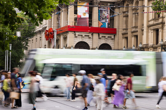 Busy urban street with people and reed tram in motion blur