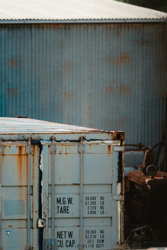 Weathered shipping container with visible rust and corrugated metal background