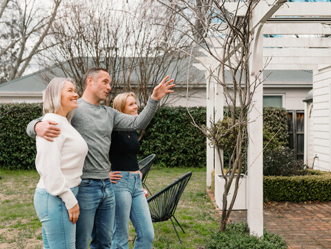 Happy family gathered in the patio of their new home with adult man pointing towards patio rafter