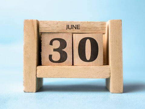 A wooden block calendar for June thirtieth on a light blue background. Perfect for deadlines or beginning-of-the-month reminders. Minimalist aesthetics appeal to modern audiences.