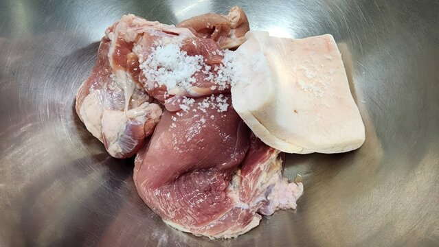Raw pork meat and fat with sea salt in a stainless steel bowl for cooking