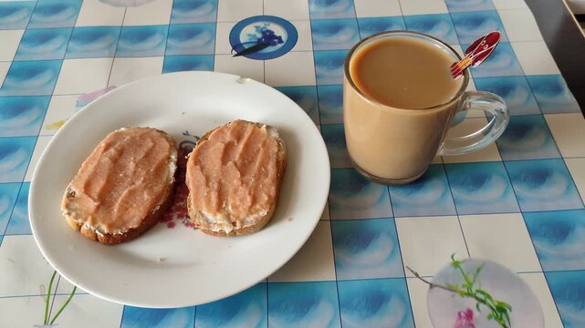 Two caviar sandwiches on plate with mug of coffee on table