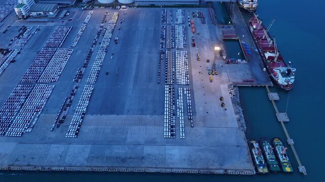 major commercial port with Ro-Ro ships, container vessels, and a massive automotive logistics parking lot. Global trade, maritime transport, and supply chain concept.	
