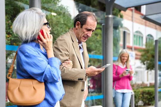 Senior couple phubbing at bus stop using smartphones