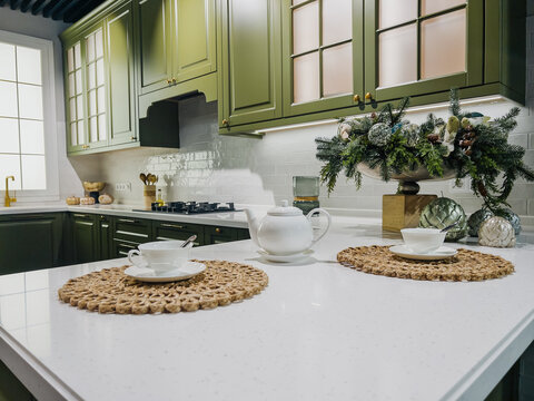 Elegant green kitchen with white countertop, teapot, two teacups and festive winter decor