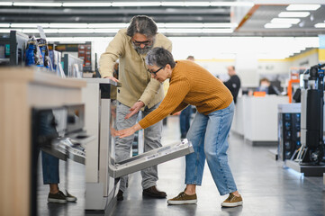Senior couple choosing dishwasher in electronics store