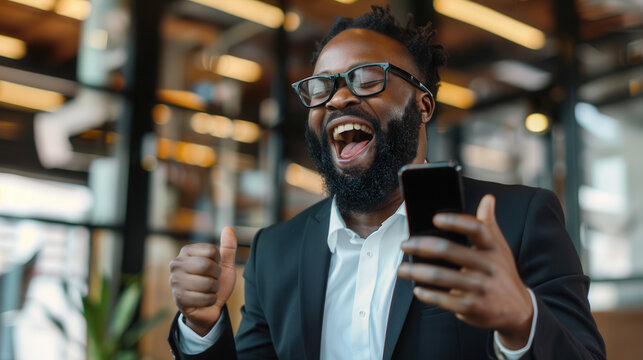 Happy professional man cheering with mobile phone during exciting workplace moment