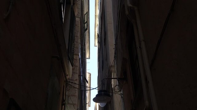 Looking up at narrow alley between tall buildings, Genoa, Italy