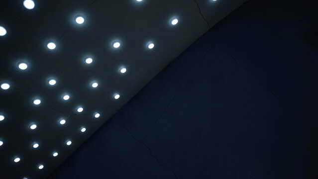Modern interior design featuring uniform ceiling spotlights on dark wall