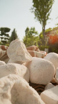 Traditional Uzbek kurt displayed outdoors in a natural setting. Close-up view of assorted dried fermented dairy snacks arranged on a rustic surface with greenery in the background. Authentic Uzbek