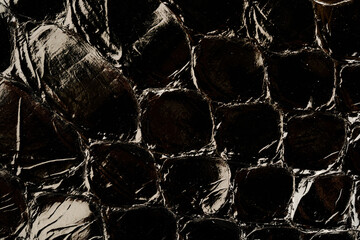Dark exotic reptile leather texture with glossy python scales for luxury fashion background © reddish