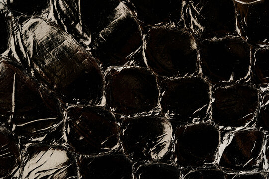 Dark exotic reptile leather texture with glossy python scales for luxury fashion background