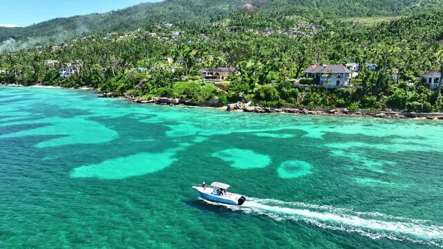 Drone shot of a boat driving by the coastline of bluefields Jamaica