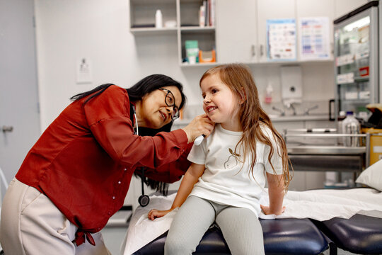 Healthcare professional examining child&rsquo;s ear with otoscope