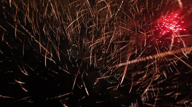 FPV aerial view of vibrant red and gold fireworks exploding in the dark night sky over Novi Sad, Vojvodina, Serbia.