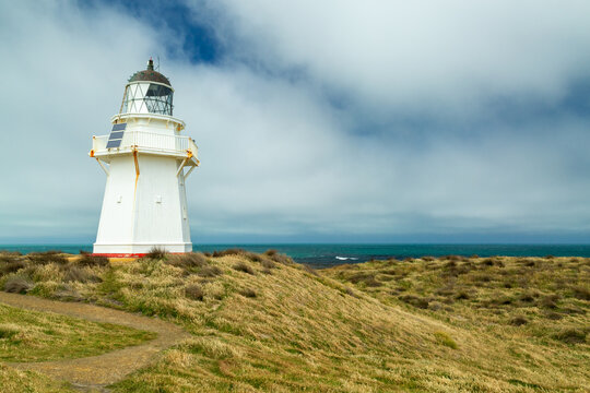 Waipapa Point Lighthouse atop grassy rolling coastal hills