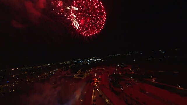 FPV aerial view of fireworks exploding in the night sky over the historic Petrovaradin Fortress with city lights in the background Novi Sad, Vojvodina, Serbia.