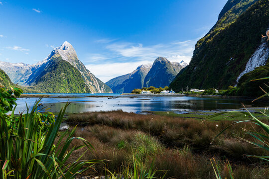 Picturesque scene across coloured grasses and blue water with reflections to mountain peaks