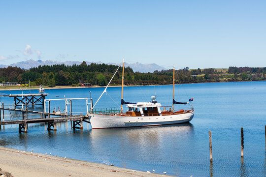 A Yacht at a jetty in a blue lake with a clear blue sky