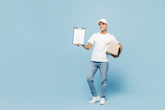 Full body delivery employee young woman wear white T-shirt uniform work as dealer courier hold in hand clipboard with paper document cardboard box isolated on plain blue background. Service concept