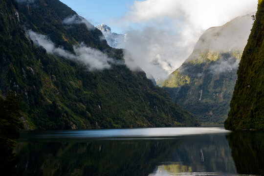 Dramatic view of light pooling in a fiord with steep mountains and low clouds