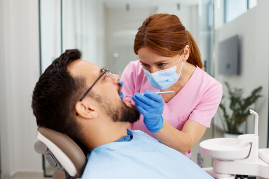 Dentist carefully inspecting patient teeth during oral examination