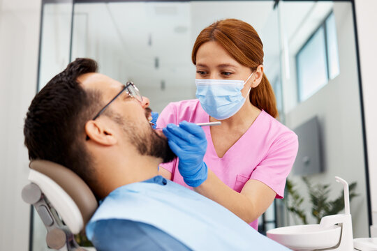 Female dentist examining male patient during dental checkup